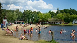 Una playa junto al lago con gente nadando y tomando el sol.