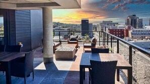 An outdoor seating area with tables and chairs, a fire pit, and a cityscape view at sunset. - 1CH + Rooftop pool+Cuisine+Smart TV+Gym+750m QC (Québec City)