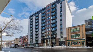 A modern multi-story building with a flat facade, large windows, and balconies. - 1CH + Rooftop pool+Cuisine+Smart TV+Gym+750m QC (Québec City)