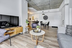 A modern living room with a wooden coffee table, a grey sofa, and a dining area with a round table and chairs. - *Penthouse* Parking+Rooftop pool+Gym+750m Vieux-QC (Québec City)