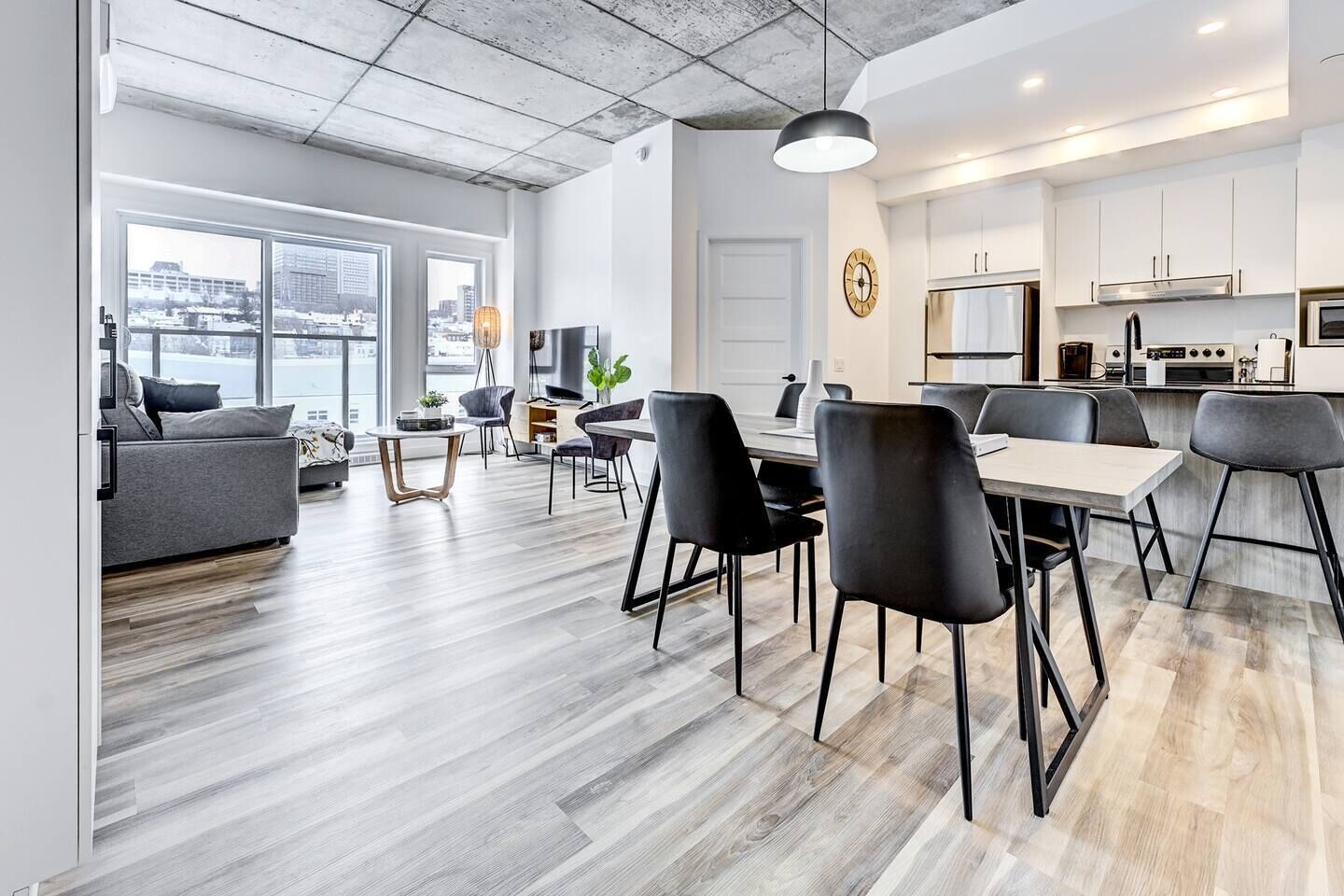 Un appartement moderne comprenant un coin repas, une cuisine et une grande fenêtre donnant sur la ville.