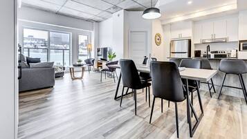 Un appartement moderne comprenant un coin repas, une cuisine et une grande fenêtre donnant sur la ville.