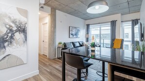 Uma área de jantar moderna com mesa de vidro, cadeiras pretas e uma garrafa de champanhe.