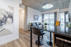 A modern dining area with a glass table, black chairs, and a bottle of champagne. - 2CH - 2SDB - 98 Walkscore-AC -rooftop pool- view (Québec City)