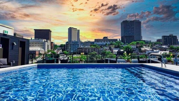 Piscina no terraço com vista para a cidade ao pôr do sol.