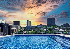 A rooftop pool with a cityscape view at sunset. - 2CH - 2SDB - 98 Walkscore-AC -rooftop pool- view (Québec City)