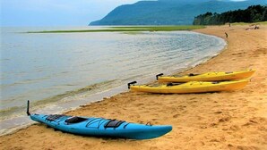 A beach with kayaks and a mountain in the background. - 4BR | Spa, Sauna, View, Billiards | Lower Unit (Petite-Rivière-Saint-François)