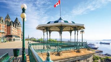 A gazebo with a Canadian flag, a waterfront view, and a historic building in the background.