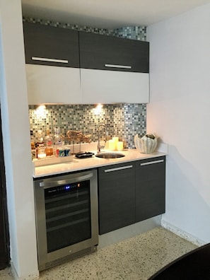 A modern kitchen with dark cabinets, a stainless steel dishwasher, and a tiled backsplash. - Beach Life Makes for a Great Life (Carolina)