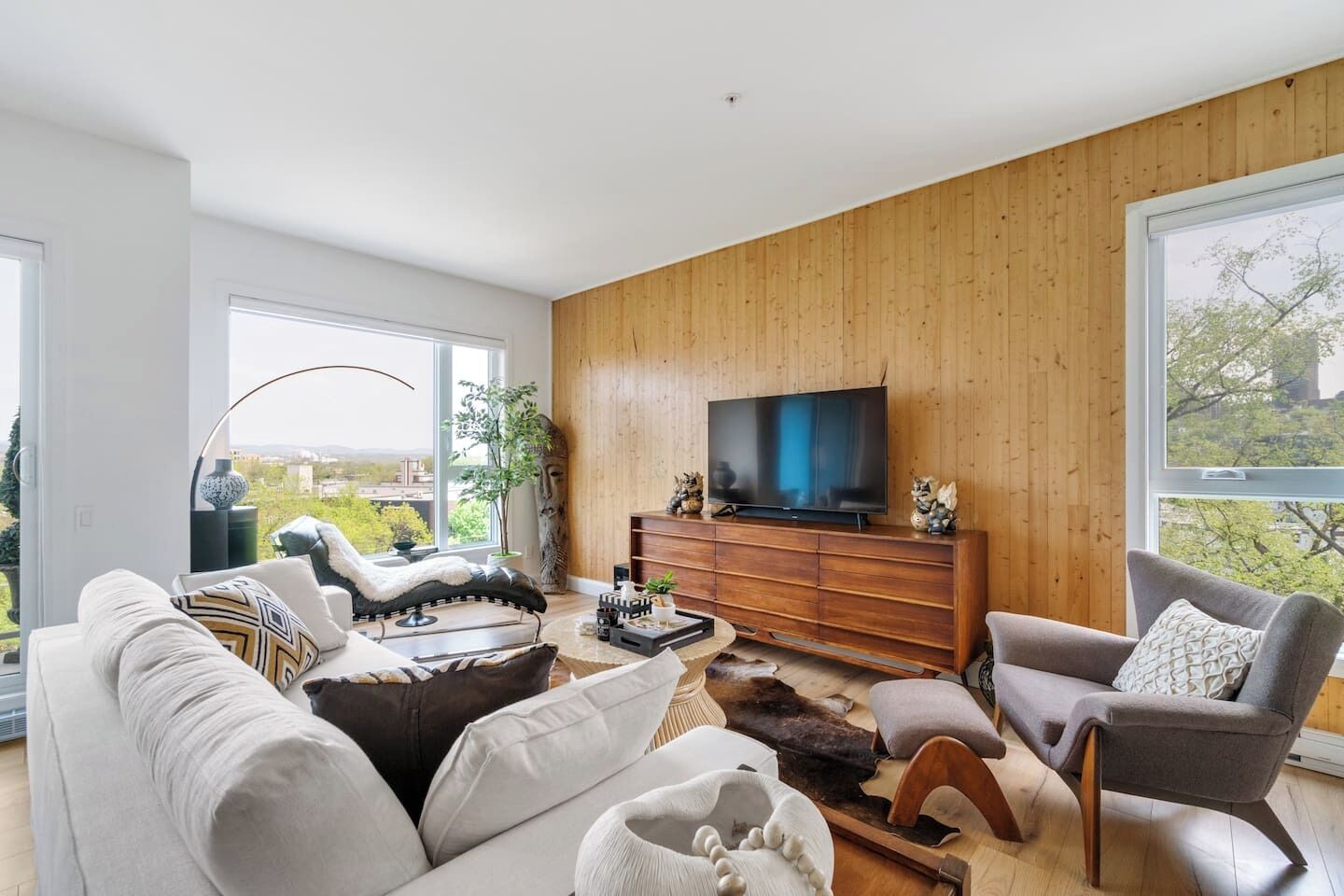 Una sala de estar moderna con un televisor grande, asientos cómodos y vistas a la ciudad.
