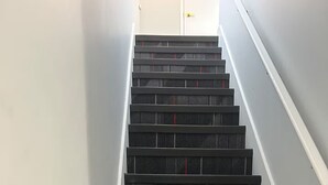 A staircase with black carpeted steps and red stripes, leading to a door at the top. - Charming Condo - Perfect for Visiting Quebec City (Québec City)