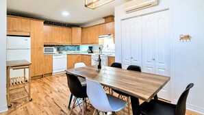 A modern kitchen with wooden cabinets, a dining table with chairs, and a dishwasher. - Charming Condo - Perfect for Visiting Quebec City (Québec City)