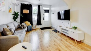 A modern living room with a sofa, a coffee table, a TV, and a white console.