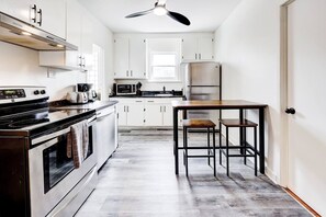 A modern kitchen with white cabinets, a stainless steel refrigerator, a microwave, and a black stove. - Modern 2BR Quebec City | 10 min Old Quebec | Patio (Québec City)