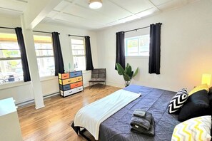 A bedroom with a bed, a dresser, a chair, and a window. - Modern 2BR Quebec City | 10 min Old Quebec | Patio (Québec City)
