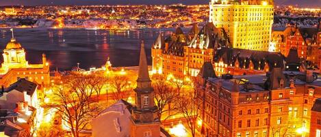 A historic building with a prominent tower and spires, surrounded by other buildings and a body of water.