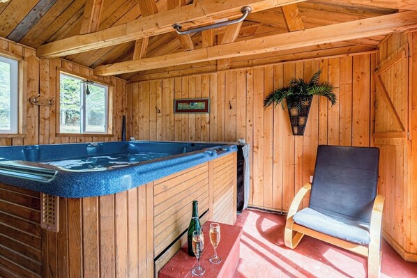 A wooden cabin with a hot tub, a chair, and a bottle of champagne. - Oasis Du Massif - Spa, BBQ, fireplace and nature (Saint-Paul-de-Montminy)