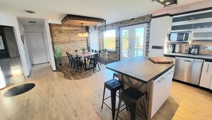 Une cuisine moderne dotée d’un îlot central, d’appareils électroménagers en acier inoxydable et d’un coin repas agrémenté d’un mur d’accent en bois.
