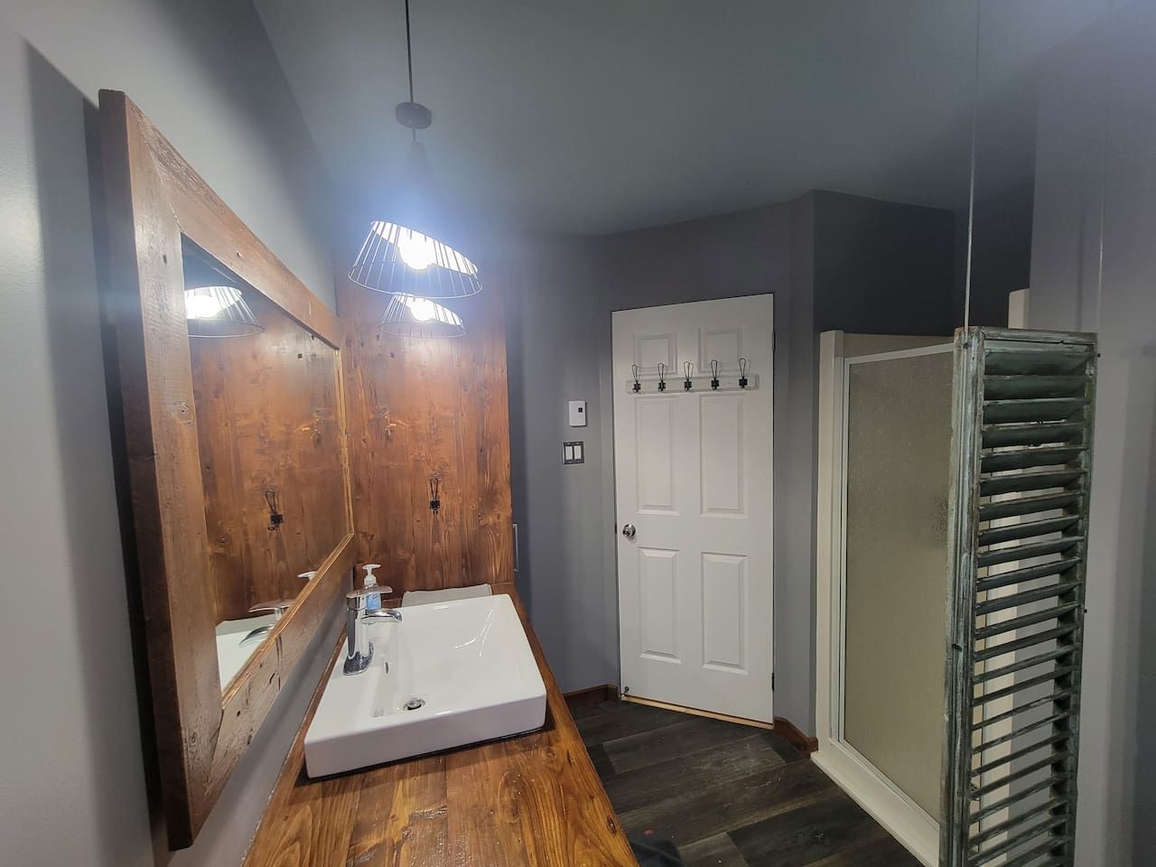 A bathroom with a wooden vanity, a white sink, and a large mirror.