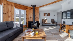 Una sala de estar acogedora con un sofá, una mesa de centro con alimentos para el desayuno, una chimenea y un mueble para la televisión.