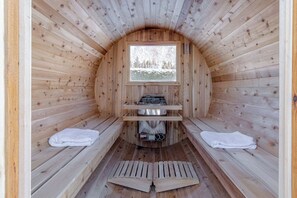 Un sauna avec des murs en bois, un banc, une fenêtre et un générateur de vapeur.