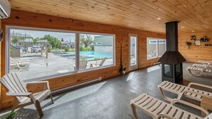 A wooden interior with a large window overlooking a swimming pool and a sauna area.