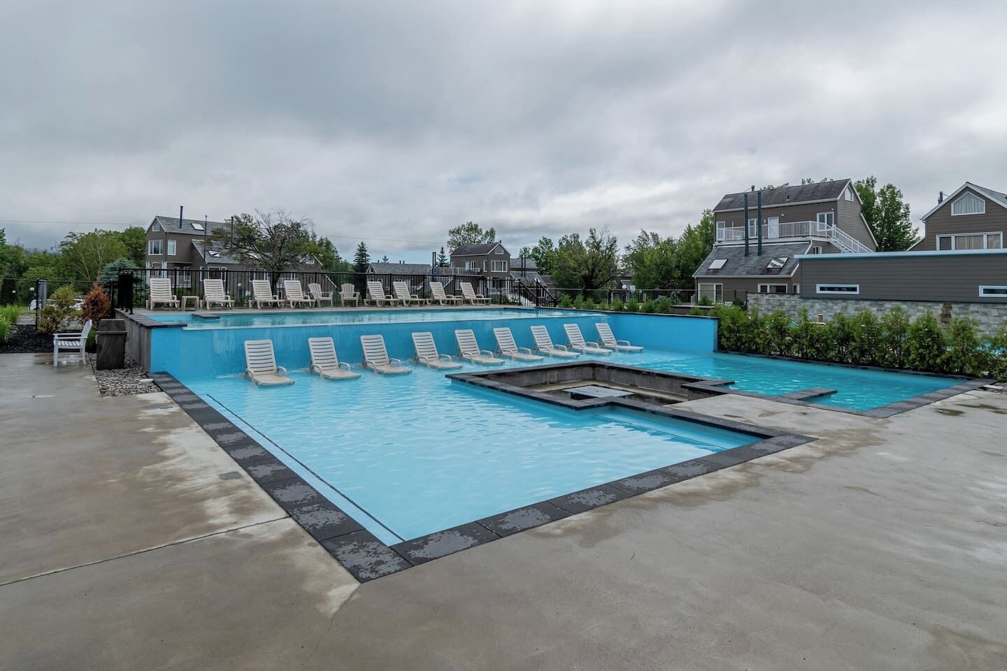 A swimming pool with multiple lounge chairs and a concrete deck.