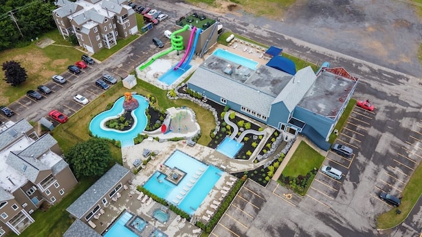 Vista aérea de un hotel con varias piscinas, un estacionamiento y un edificio con techo azul.