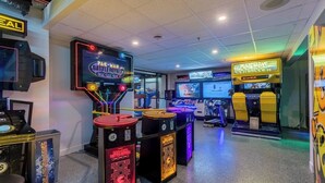 Una sala de juegos con varias máquinas, incluyendo Pac-Man Battle Royale, y un letrero iluminado con neón.