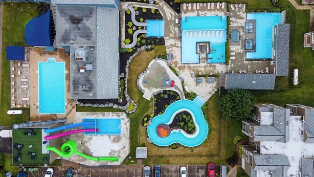 An aerial view of a resort with multiple swimming pools, a children's play area, and a parking lot. - MSA condo with year-round heated pool and spa! (Beaupré)