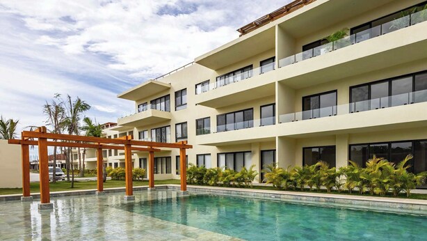 A modern hotel with a pool, multiple balconies, and tropical landscaping. - Garden-view patio retreat w/ pool & BBQ (Tondoroque)