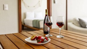 A wooden table with a bottle of red wine, two wine glasses, and a plate with sliced apples and strawberries. - Garden-view patio retreat w/ pool & BBQ (Tondoroque)