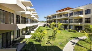 A modern hotel with a central courtyard, multiple balconies, and a clear view of the surrounding landscape. - Garden-view patio retreat w/ pool & BBQ (Tondoroque)