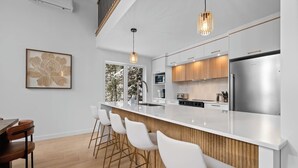 Una cocina moderna con encimera blanca, electrodomésticos de acero inoxidable y una pared de acento de madera.