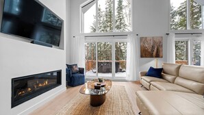 Una sala de estar moderna con chimenea, televisor grande y sofá.