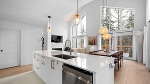Una cocina moderna con una isla grande, electrodomésticos integrados e iluminación colgante.