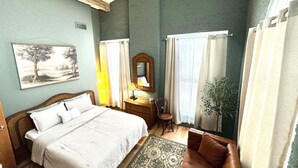 Een slaapkamer met een bed, bureau, stoel en spiegel.