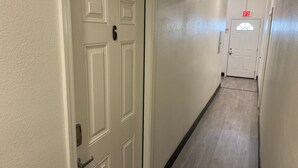 En hall med en vit dörr som är märkt med nummer 6, och som leder till en utgångsdörr med en skylt som visar ”UTGÅNG”.