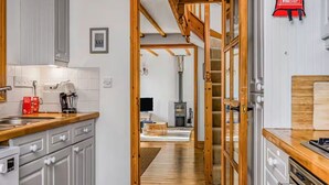 A kitchen with wooden cabinets, a coffee machine, and a red fire extinguisher. - Charming Family Stables Conversion - Pass the Keys (Emsworth)