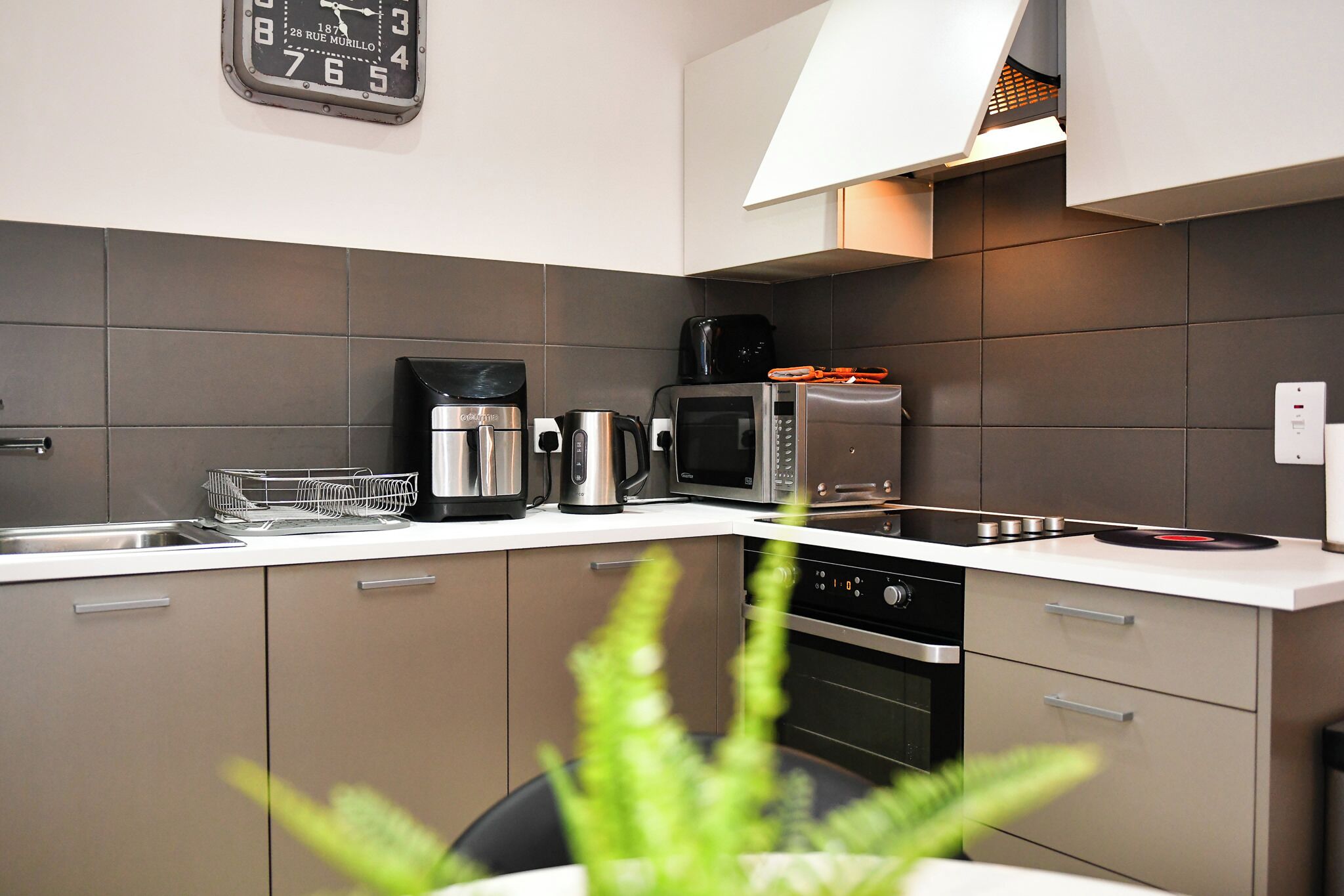 Een moderne keuken met een magnetron, koffiezetapparaat en waterkoker op het aanrecht.
