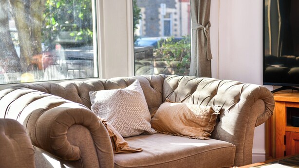 Un salon confortable avec un canapé moelleux, un téléviseur et une vue sur l’extérieur grâce à une grande fenêtre.