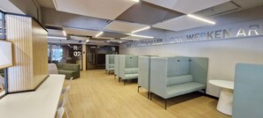 Een moderne kantoorruimte met kantoorkamers, een receptie en een bord waarop 'OBAIRADIT TRAVAILLER WORKWERKEN' staat.