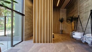 Interior moderno com porta de vidro que dá para o exterior, parede com ripas de madeira e bolsas penduradas.