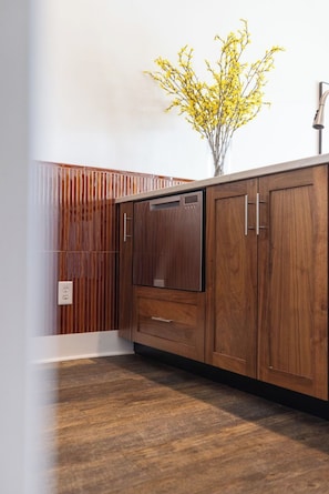 A kitchen with wooden cabinets, a built-in dishwasher, and a wooden backsplash. - The Lantern Loft | Luxury Riverfront Downtown (Wilmington)