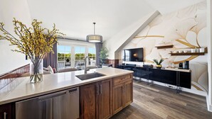 A modern kitchen with a large island, built-in appliances, and a dining area with a view. - The Lantern Loft | Luxury Riverfront Downtown (Wilmington)