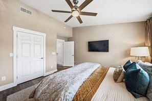 A hotel room with a bed, a ceiling fan, a TV, and a window with curtains. - The Lantern Loft | Luxury Riverfront Downtown (Wilmington)