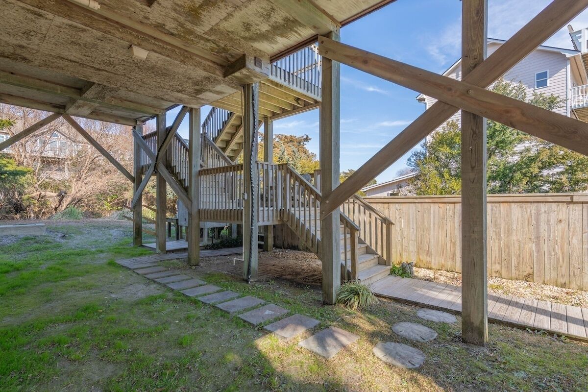 A wooden deck structure with a staircase leading to a covered area.