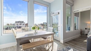 Un appartement moderne doté d’un coin repas, de grandes fenêtres et offrant une vue sur la ville.