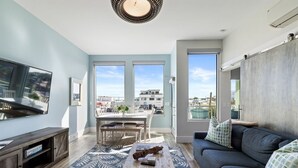 Un salon moderne doté d’un grand téléviseur, d’un coin repas et d’un canapé offrant une vue sur la ville.