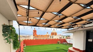 An outdoor patio with artificial grass, blue chairs, and tables with Coca-Cola branding. - Casa Tita penthouse with rooftop in downtown Querétaro (Santiago de Querétaro)